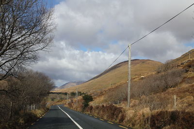 Country road amidst landscape against sky