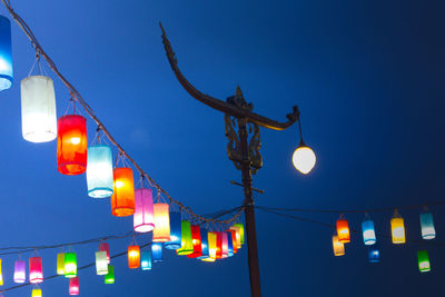 Low angle view of illuminated street light against blue sky