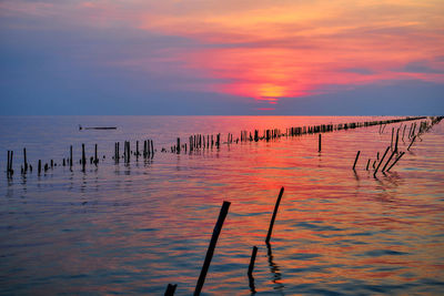 Sunset over the sea with vivid sky and wooden post