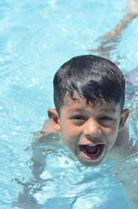 High angle portrait of boy screaming while swimming in pool