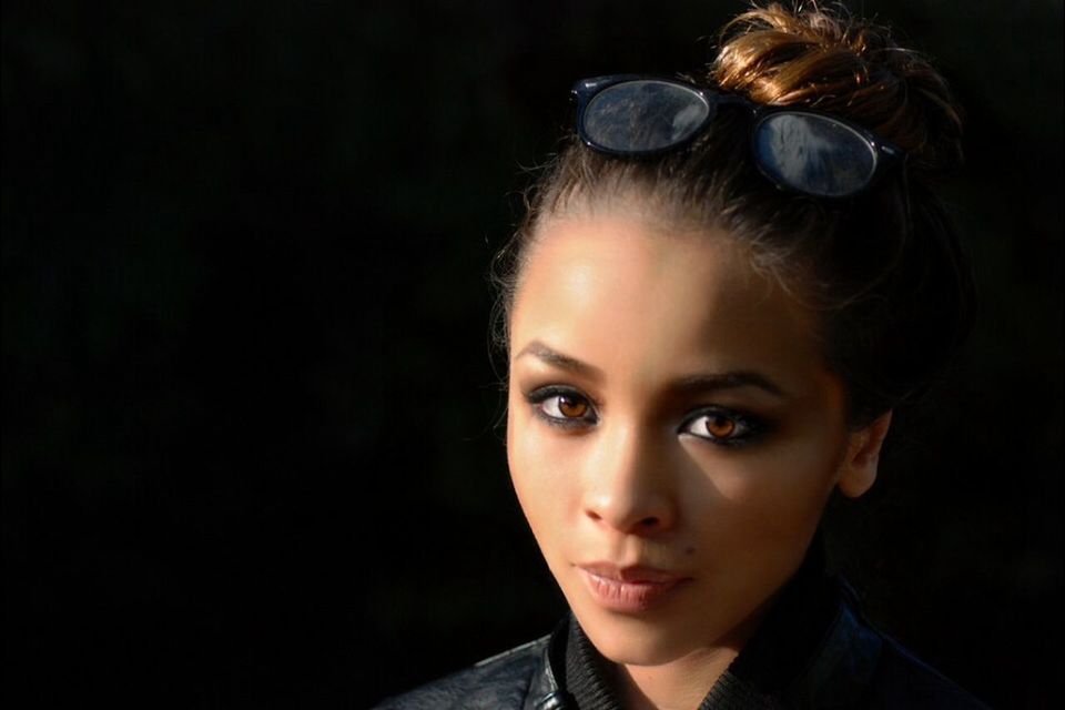 headshot, looking at camera, portrait, person, human face, close-up, lifestyles, young adult, front view, studio shot, head and shoulders, leisure activity, black background, serious, focus on foreground, young women, contemplation