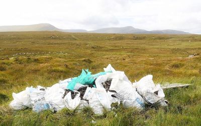 Garbage on field by mountain against sky