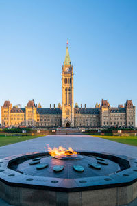 Fountain and buildings against clear blue sky