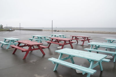 Empty picnic table on land with sea in background against clear sky