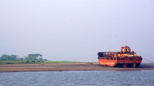 Shipwreck at beach against clear sky