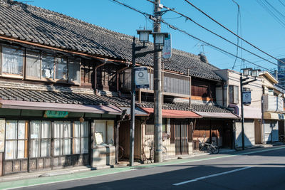 Road by buildings against clear sky