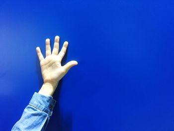 Cropped hand against blue wall