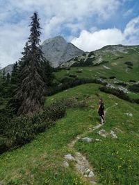 Woman walking on mountain against sky