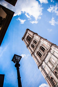 Low angle view of street light by building against sky