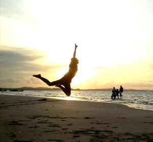 Silhouette people on beach against sky during sunset