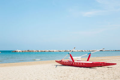 Boat moored on beach against sky