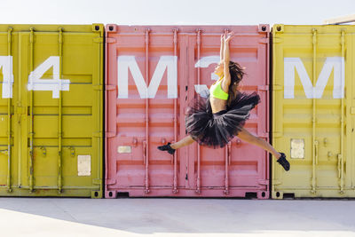 Ballet dancer dancing against cargo containers