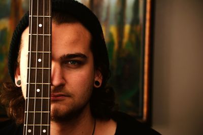 Close-up portrait of handsome man in front of guitar at home