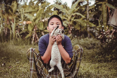 Portrait of teenage boy with cat on field