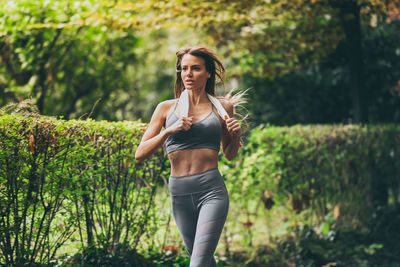 Determined young woman running outside in the park. fit girl doing exercise outdoor. female runs