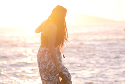 Woman standing at beach during sunset