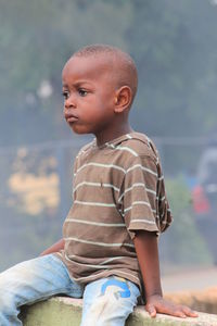 Cute boy looking away while sitting outdoors