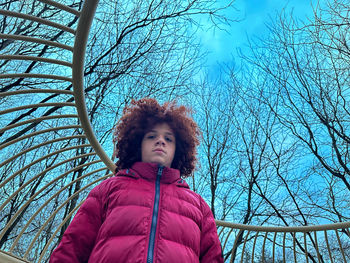 Portrait of young woman standing against bare trees