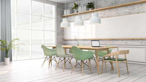 Pendant lights hanging over table amidst chairs at home