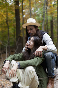 Young couple sitting on tree in forest