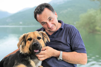 Portrait of man with dog against lake