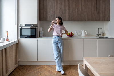 Side view of young woman using mobile phone while sitting in bathroom