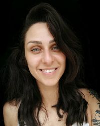 Portrait of smiling young woman against black background