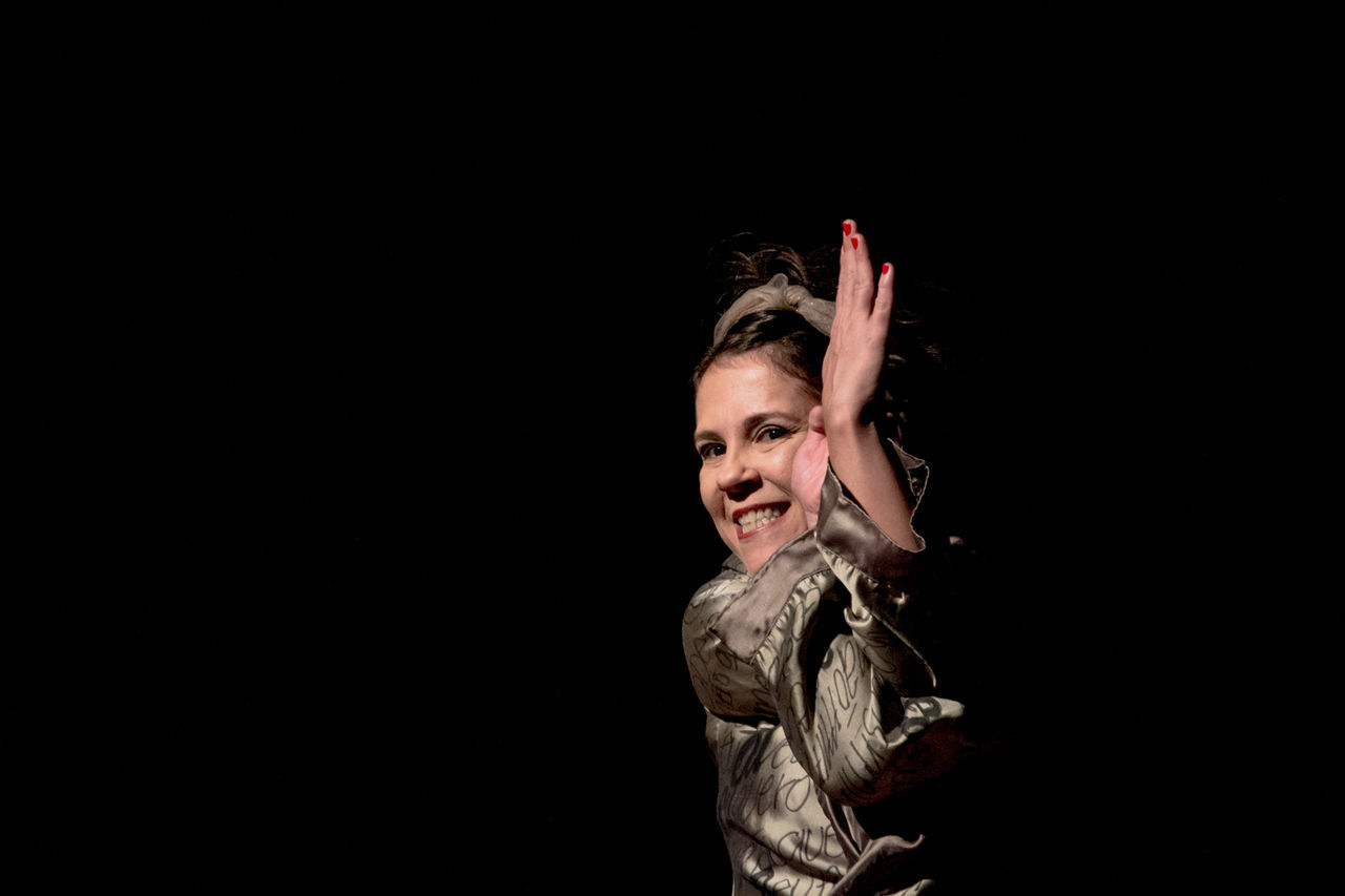 black background, studio shot, one person, copy space, indoors, portrait, young adult, looking at camera, human arm, emotion, smiling, arms raised, gesturing, adult, hair, happiness, waist up, limb, human limb, hairstyle