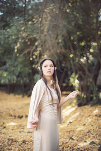 Thoughtful fairy elf young woman standing by trees during autumn