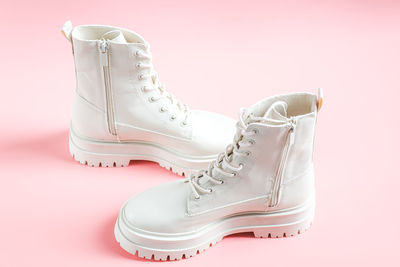 White demi-season martens boots made of eco-leather with a rough sole stand on a pink.