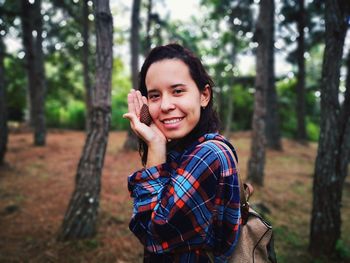 Portrait of smiling woman holding pine cone