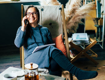 Young woman using phone while sitting on table