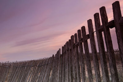 Low angle view of wooden fence on landscape against sky