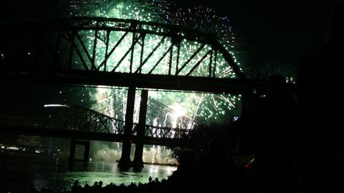 Silhouette people on illuminated bridge at night