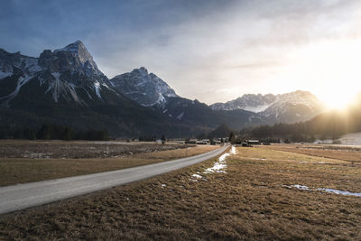 Empty road leading towards snowcapped mountains against sky