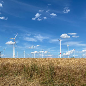 Wind turbines on field against sky