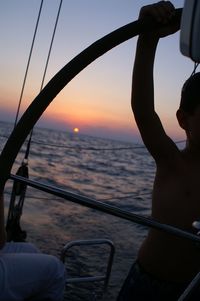 Silhouette person in sea against sky during sunset