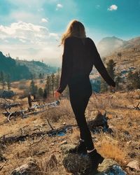 Rear view of woman standing on land against sky