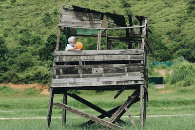 Mature woman with balloon standing on hut at field