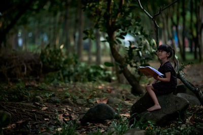 Little child reading a book in a green coastal forest