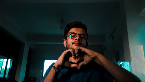 Portrait of young man holding eyeglasses at home