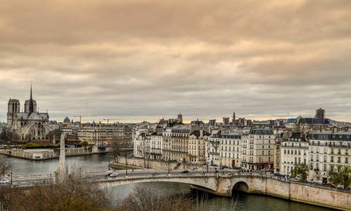 Bridge over river against cloudy sky