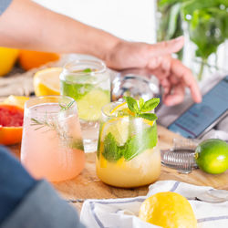 Mixologist making hard seltzer cocktails while watching instructional video on phone at home.