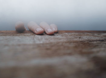 Close-up of human hand  on wood board in fog