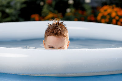 Portrait of a funny white kid peeking out of the pool