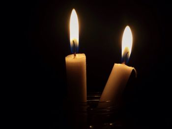 Close-up of lit candle in darkroom