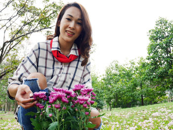 Portrait of smiling young woman holding flowering plants