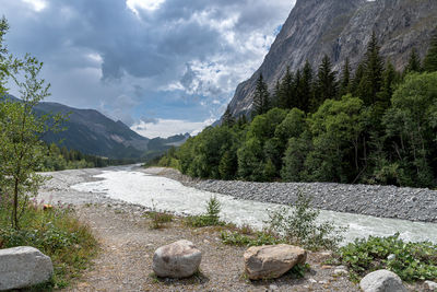 Scenic view of river by mountains against sky