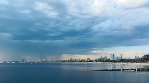 City at waterfront against cloudy sky