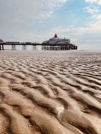 View of pier on beach against cloudy sky